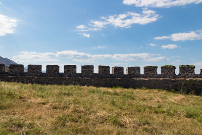Buildings in field against cloudy sky