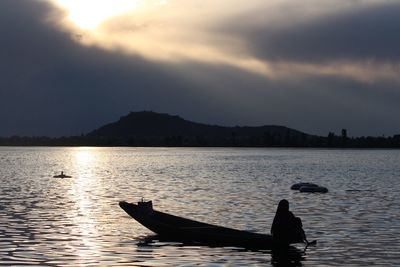 Silhouette woman in lake against sky during sunset