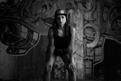 Portrait of woman standing against graffiti wall