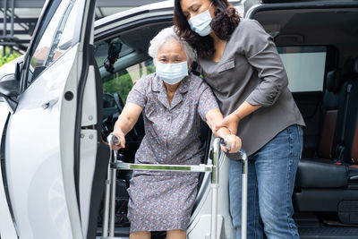 Caregiver help and support asian senior woman patient walk with walker prepare get to her car.