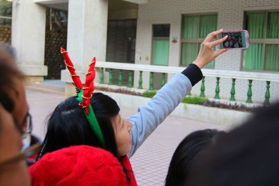 Side view of young woman standing against building