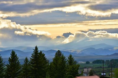 Scenic view of trees and mountains against sky at sunset