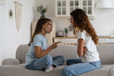 Young woman using phone while sitting on sofa at home