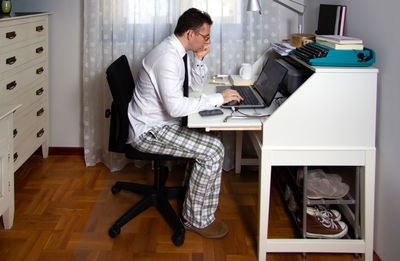 Full length of man sitting on table at home