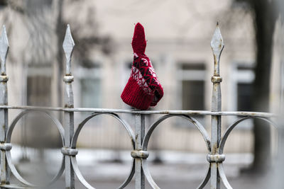 Red patterned ethnic glove / mitten / attached on the sharp, metal, fence spike.