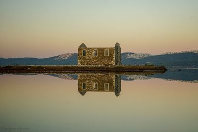 Reflection of building in lake against clear sky