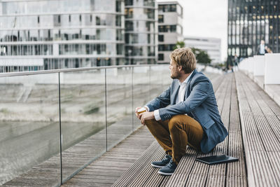 Businessman sitting on bridge having coffee break