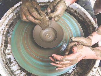 Cropped hands shaping clay on pottery wheel