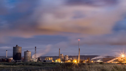 Smoke emitting from factory against sky