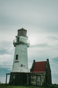 Low angle view of lighthouse by building against sky