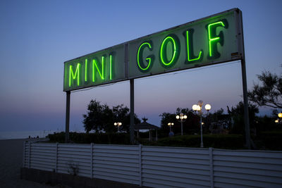 Information sign on road against sky at night