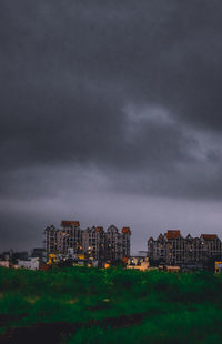 Buildings in city against storm clouds