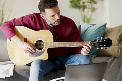 Man playing guitar on sofa