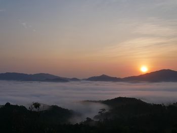 Scenic view of dramatic sky over silhouette mountains during sunset