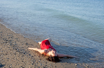High angle view of woman lying on shore at beach