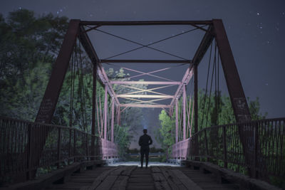 Rear view of man on footbridge against sky