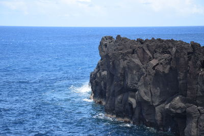 Rock formation in sea against sky