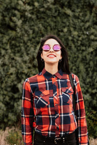 Portrait of smiling young woman standing against plants