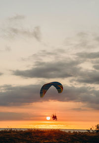 People paragliding against sky during sunset