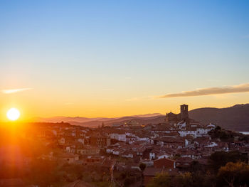Buildings in town against sky during sunset