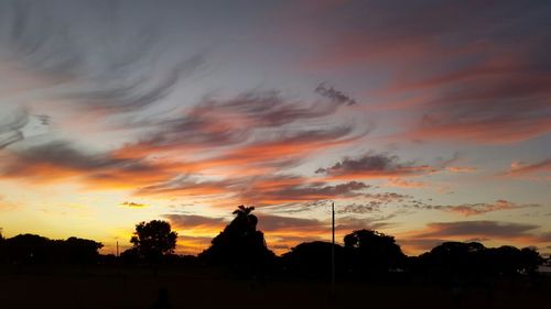 Silhouette trees against dramatic sky during sunset