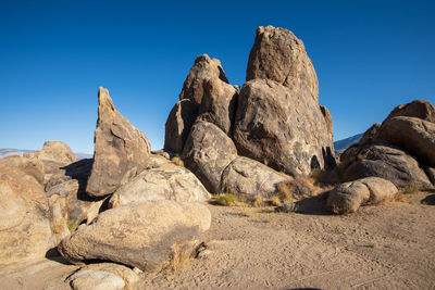 Low angle view of rocks against clear blue sky