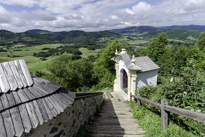 High angle view of steps leading towards green landscape against cloudy sky