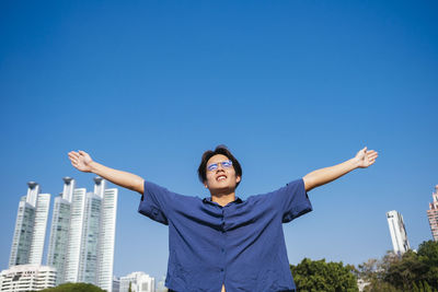 Low angle view of smiling man standing against blue sky