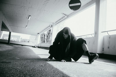 Side view of man sitting on footpath in city