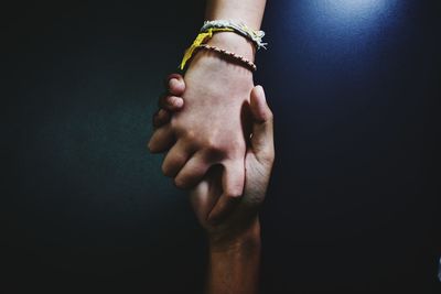 Close-up of hand holding hands over black background