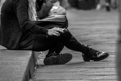 Low section of woman sitting on sidewalk