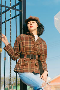 Young woman wearing hat standing against blue sky