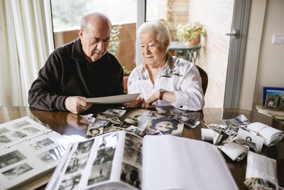 Senior couple watching their old photographies and photo albums at home