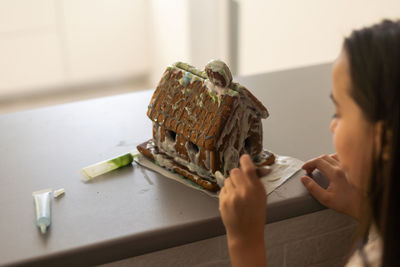 A girl plays with a gingerbread house for traditional christmas decoration