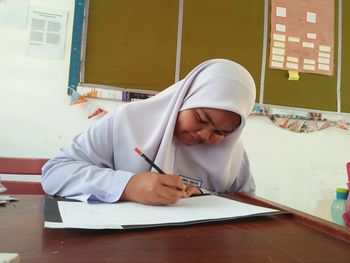 Teenage girl writing on paper