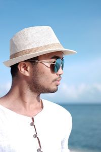 Young man wearing hat and sunglasses by sea