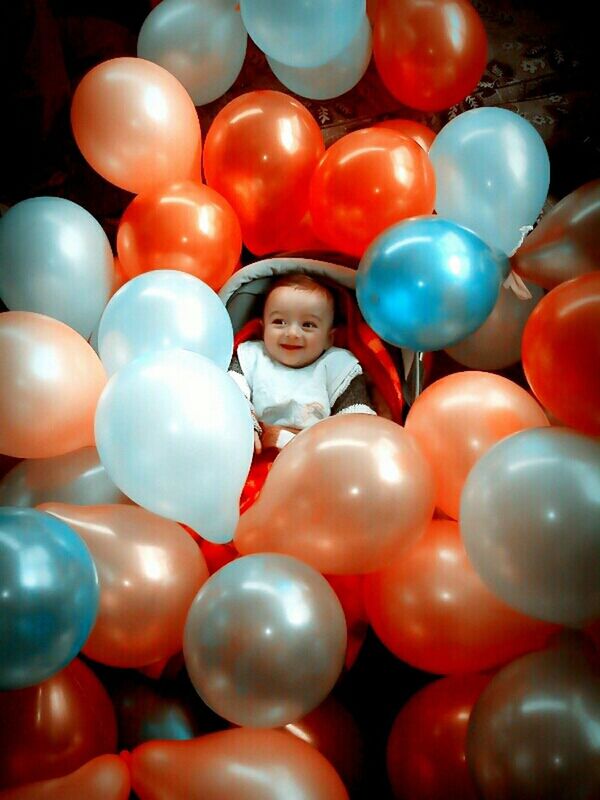 childhood, multi colored, large group of objects, portrait, looking at camera, balloon, abundance, fun, happiness, indoors, elementary age, lifestyles, leisure activity, smiling, toy, celebration, variation, ball