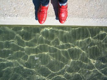 Low section of man standing by water