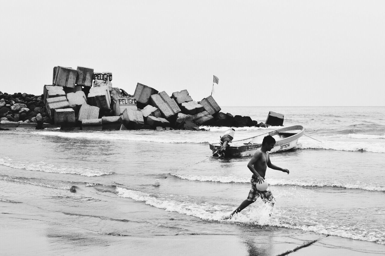 MAN ON BEACH AGAINST CLEAR SKY