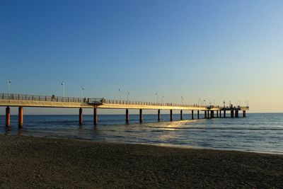 Pier over sea against clear sky during sunset