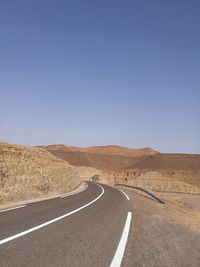 Empty road on desert against clear blue sky