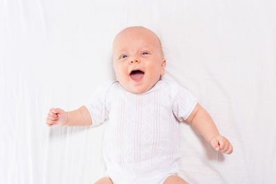 High angle view of smiling baby lying on bed at home