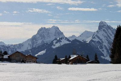 Houses by mountains against sky during winter