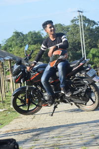 Portrait of young man riding motorcycle on road