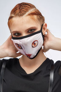 Close-up portrait of woman wearing mask against white background
