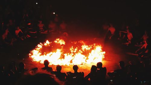 Silhouette people against fire at night