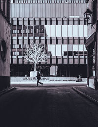 Rear view of man walking on street against buildings in city