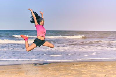 Full length of woman jumping on beach