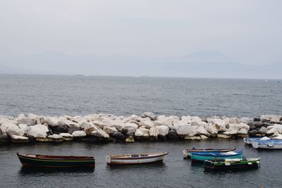 Boats moored in sea against sky