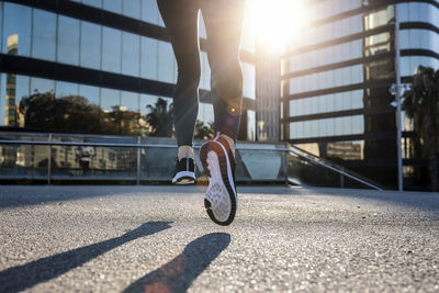 Young woman running on footpath in city